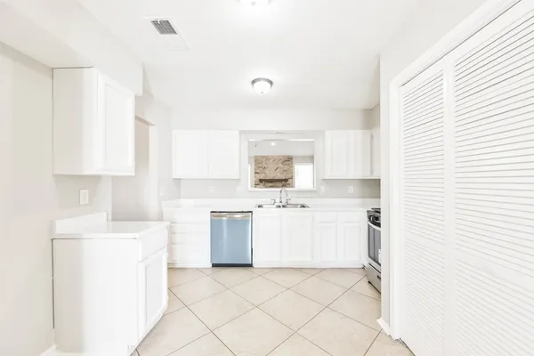a kitchen with a sink a stove a refrigerator and white cabinets
