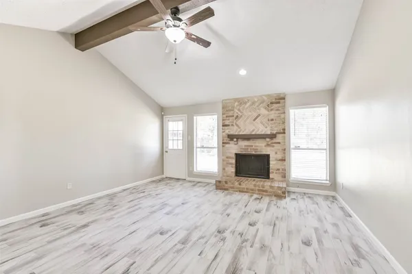 wooden floor fireplace and windows in an empty room