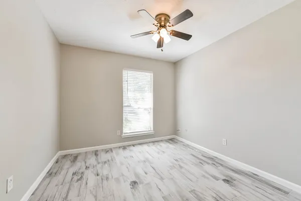 an empty room with a window and a fan