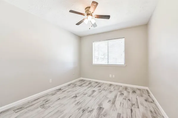 an empty room with a window and a ceiling fan