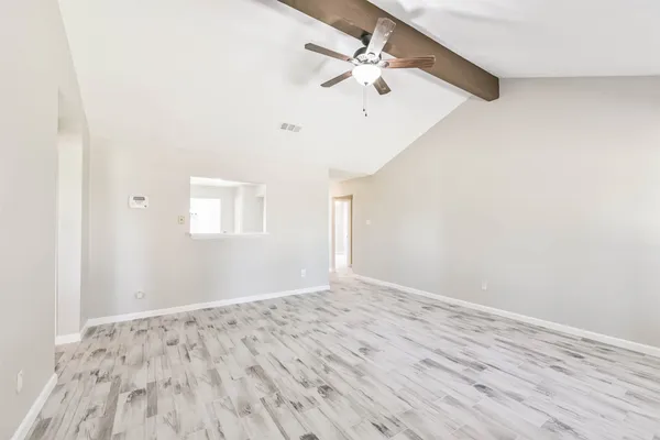 an empty room with wooden floor fan and windows
