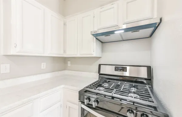 a kitchen with granite countertop a stove and a white cabinets