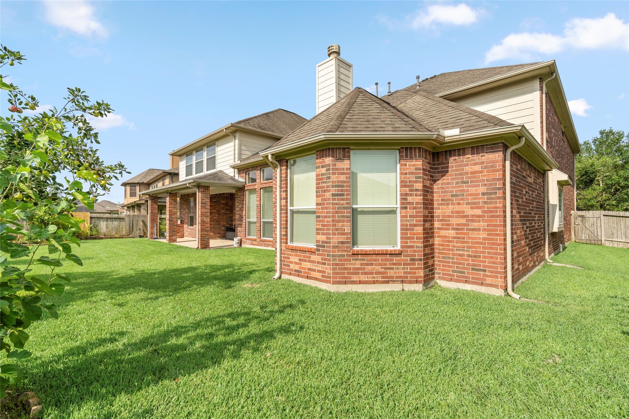 5307 Amber Sky Lane Rosharon, TX 77583 - Photo 46 of 50 The elegant all-brick exterior continues seamlessly into the backyard, showcasing timeless architecture against a backdrop of manicured greenery.