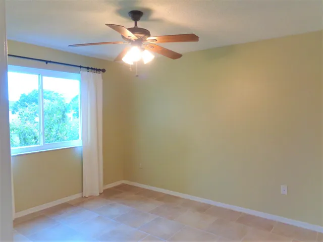 an empty room with a fan and a chandelier fan