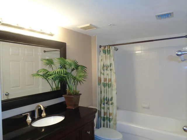 a bathroom with a sink a light fixture and a vase of flowers