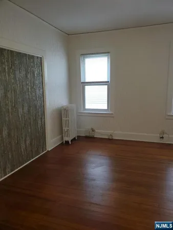 an empty room with wooden floor and windows with curtains