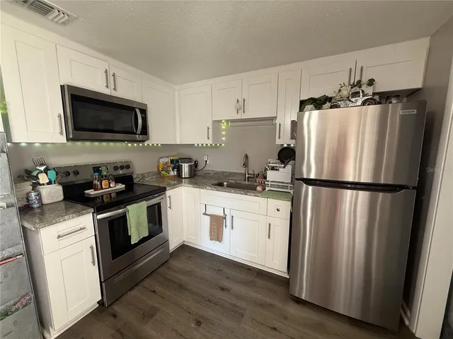 a kitchen with white cabinets stainless steel appliances and wooden floor