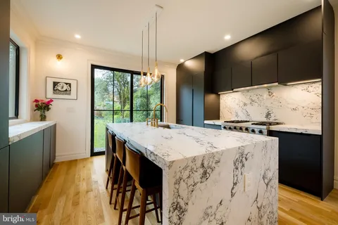 a kitchen with kitchen island a counter top space a sink a refrigerator and wooden floor