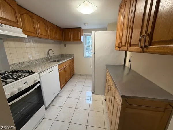a kitchen with a sink a stove top oven and cabinetry