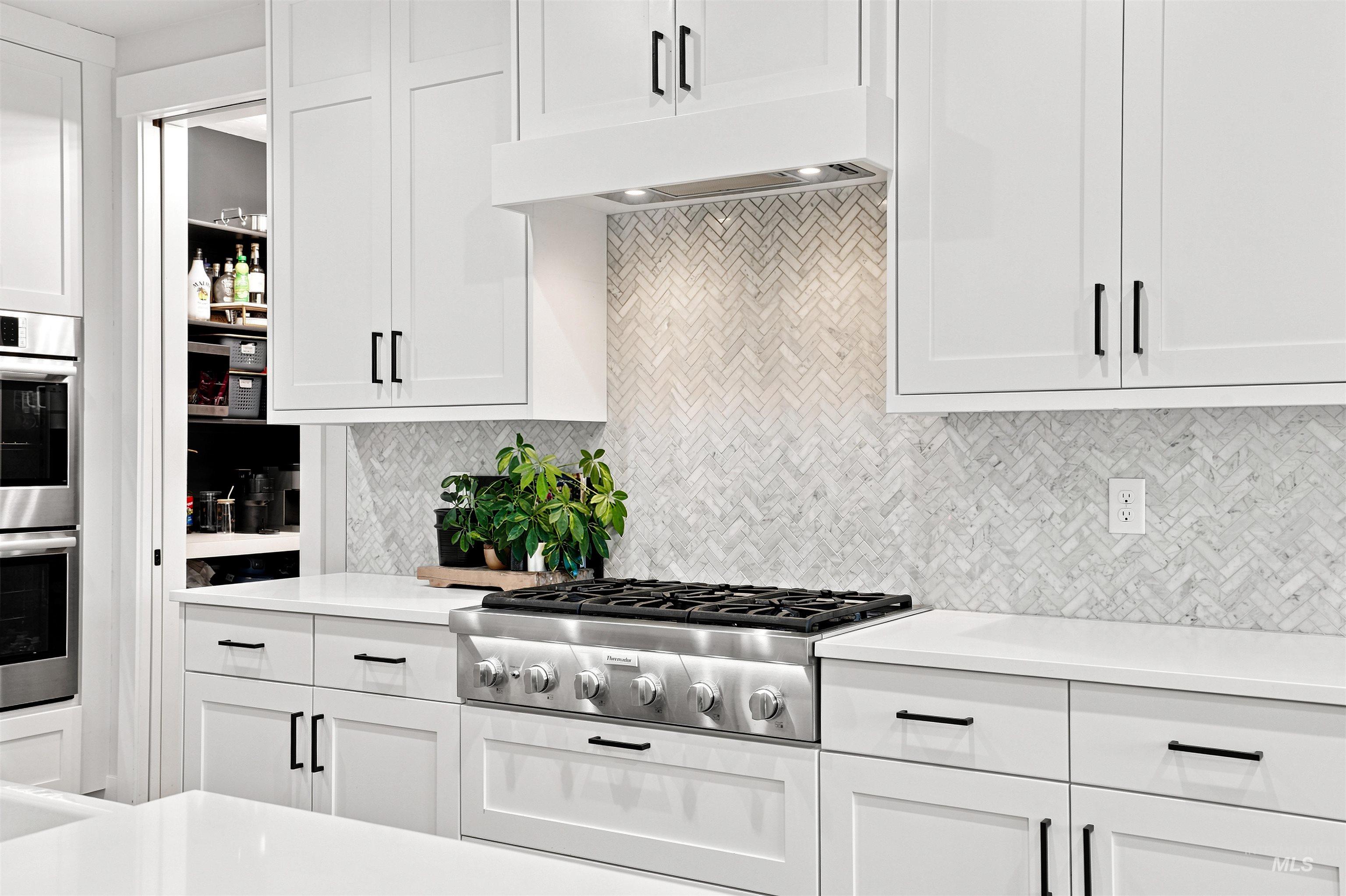 4323 West Ladle Rpds Drive Meridian, ID 83646 - Photo 11 of 49 Kitchen featuring a stainless steel gas range, white shaker cabinetry with dark hardware, a herringbone pattern tile backsplash, and light-toned countertops