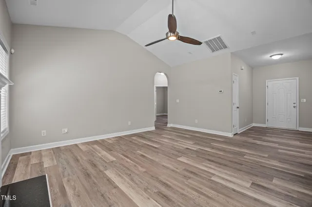 an empty room with wooden floor fireplace and windows