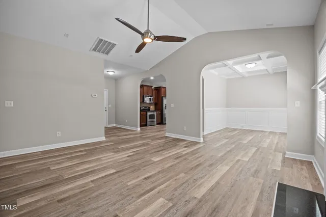 an empty room with wooden floor fireplace and windows