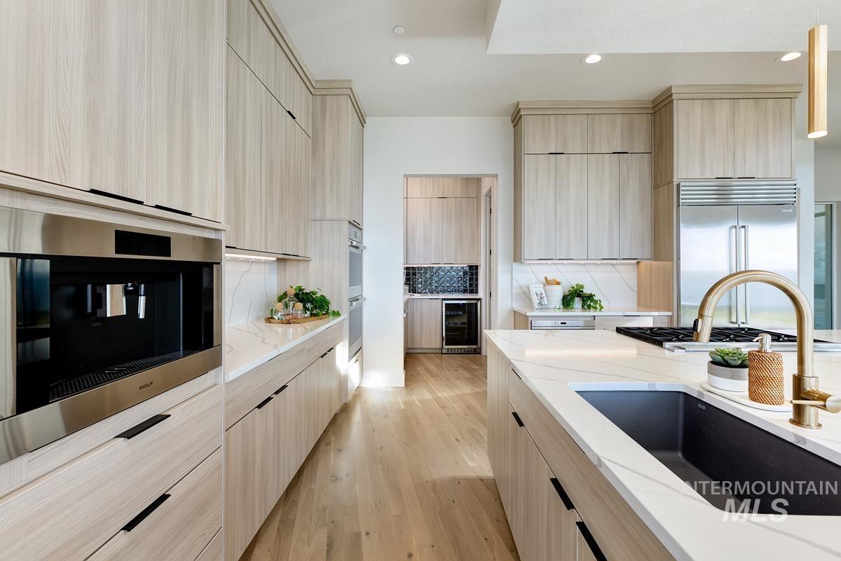5825 East Prominence Court Boise, ID 83716 - Photo 13 of 45 Kitchen with light brown cabinets, light stone countertops, light wood finished floors, modern cabinets, and recessed lighting