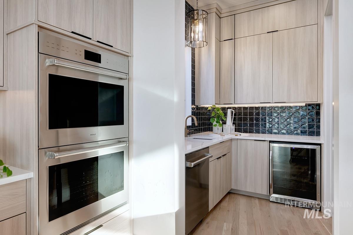 5825 East Prominence Court Boise, ID 83716 - Photo 14 of 45 Kitchen featuring stainless steel appliances, light brown cabinets, pendant lighting, wine cooler, and light stone counters