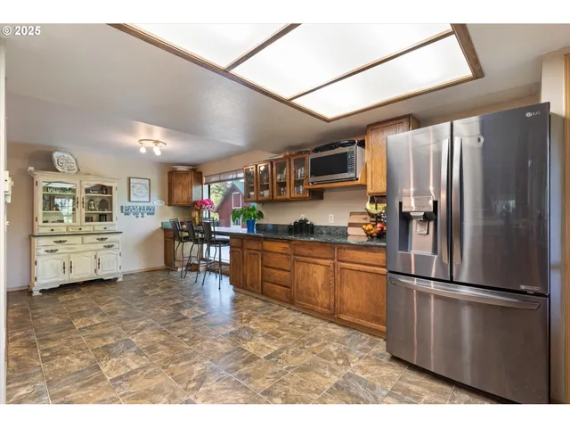 a kitchen with stainless steel appliances granite countertop a refrigerator a stove a sink dishwasher and a refrigerator with wooden floor