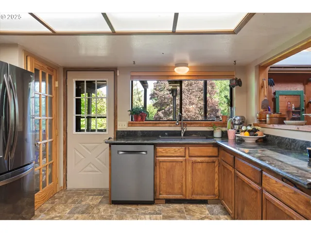 a kitchen with stainless steel appliances granite countertop a sink and a refrigerator