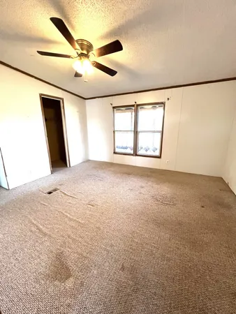 an empty room with windows and ceiling fan