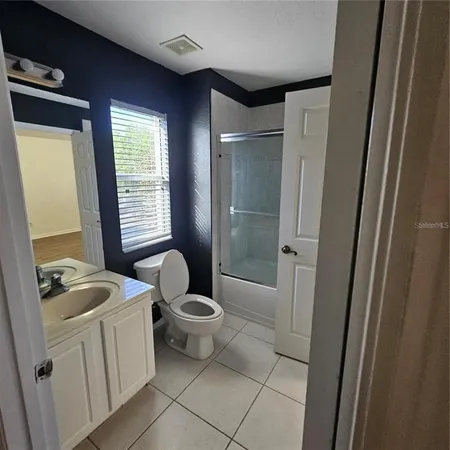 a bathroom with a toilet a sink a mirror and shower
