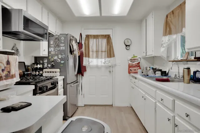 a kitchen that has a lot of cabinets a refrigerator and a sink