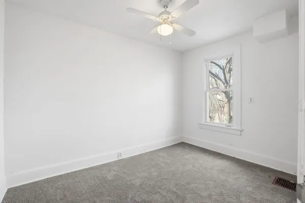 an empty room with windows and fan