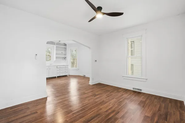 an empty room with wooden floor cabinet and windows