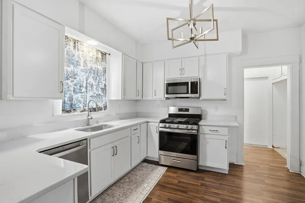 a kitchen with stainless steel appliances granite countertop a stove a sink and a microwave