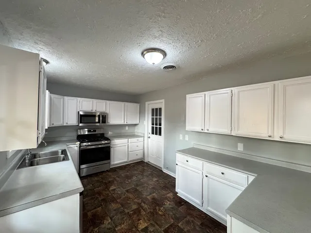 a kitchen with stainless steel appliances granite countertop a stove a sink and a refrigerator