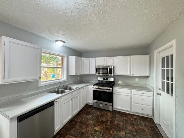 a kitchen with stainless steel appliances white cabinets a sink a stove a microwave a sink and cabinets