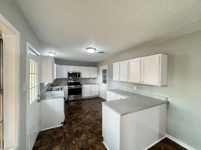 a kitchen with a refrigerator a stove top oven and white cabinets