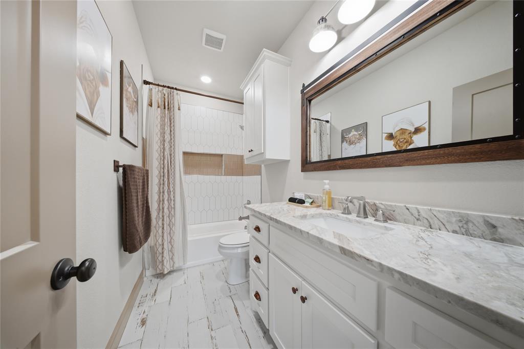 958 Cedar Mills Road Gordonville, TX 76245 - Photo 31 of 40 a bathroom with a granite countertop sink a toilet a mirror and shower
