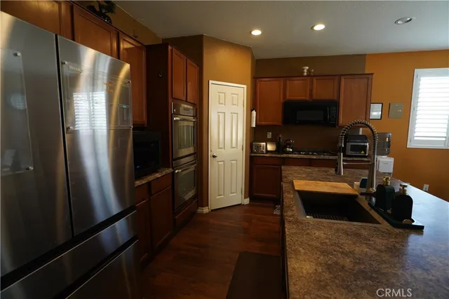 a kitchen with stainless steel appliances granite countertop a refrigerator a stove and a sink