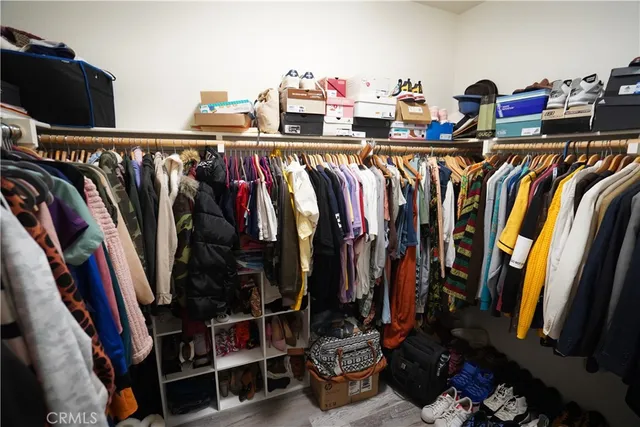 a view of walk in closet with clothes and shoes
