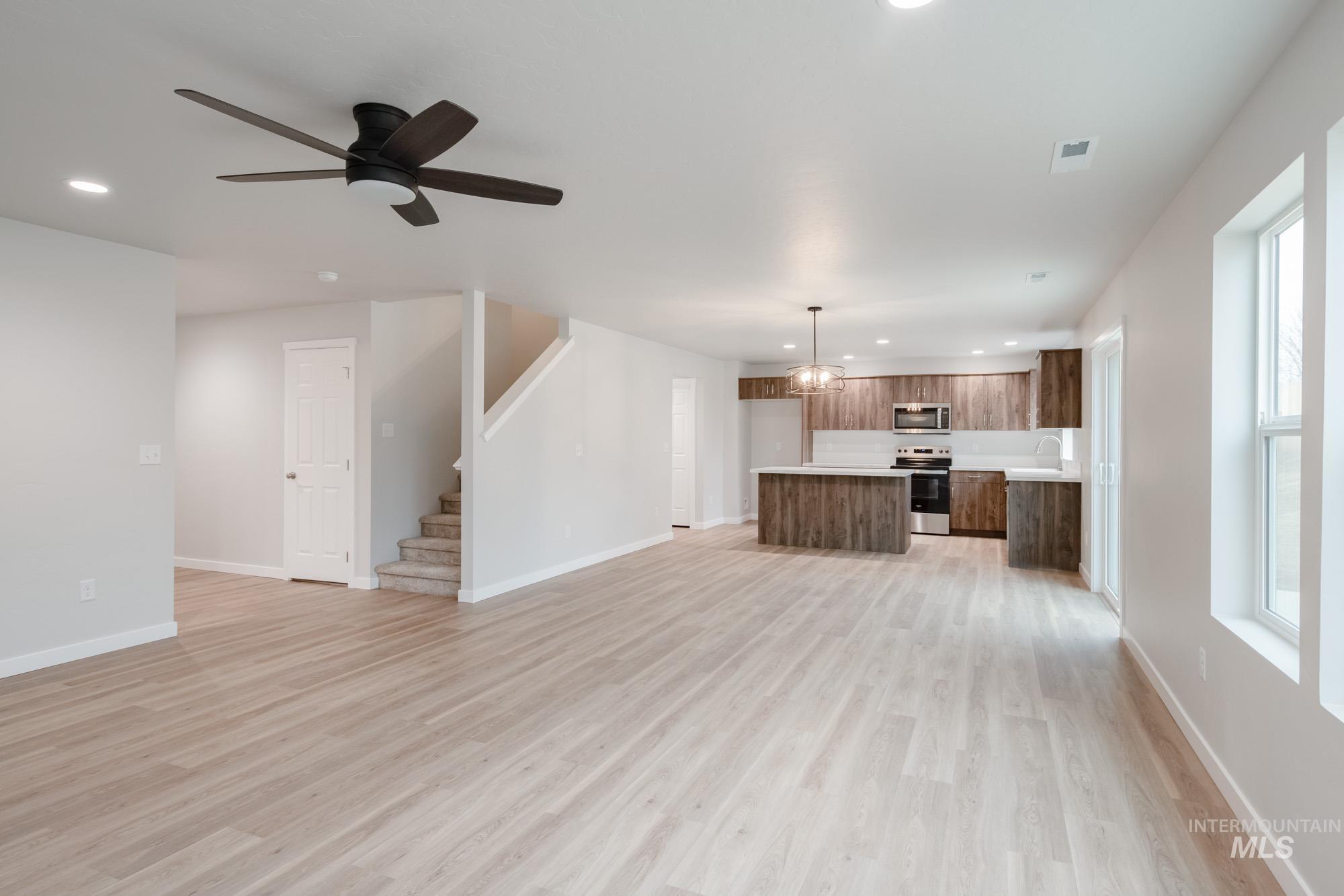 1494 Long Pond Street Middleton, ID 83644 - Photo 14 of 25 Unfurnished living room featuring recessed lighting, ceiling fan, light wood finished floors, stairs, and a chandelier