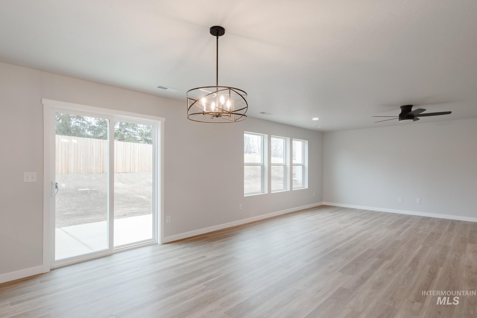 1494 Long Pond Street Middleton, ID 83644 - Photo 9 of 25 Empty room with light wood finished floors, a chandelier, ceiling fan, and recessed lighting