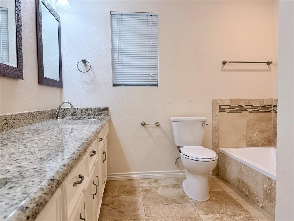 4737 Thunder Road Dallas, TX 75244 - Photo 12 of 17 a bathroom with a granite countertop sink a toilet a mirror and bathtub