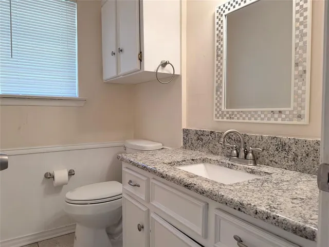 a bathroom with a granite countertop toilet sink and mirror