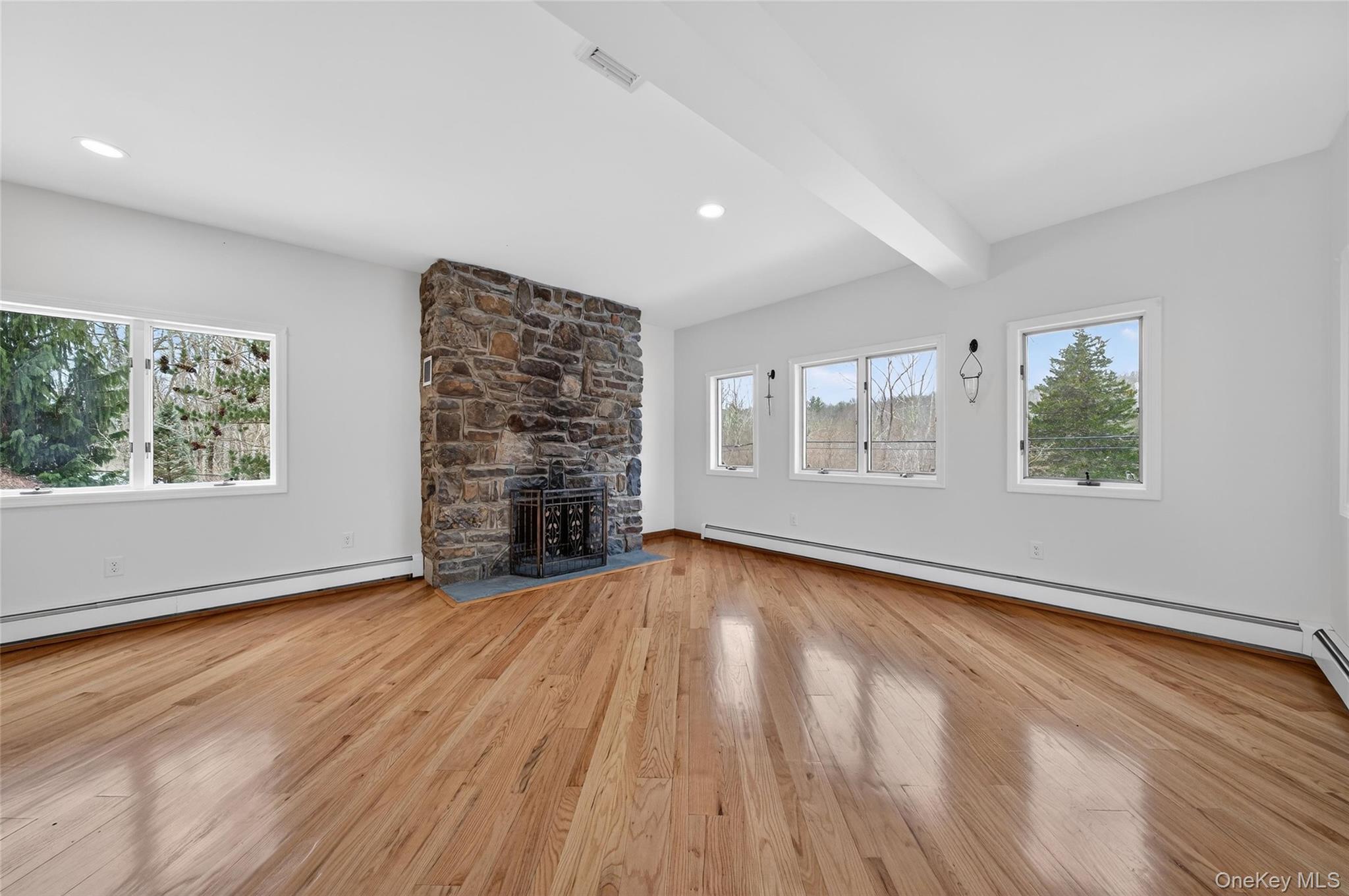 558 Pine Hill Road Chester, NY 10918 - Photo 10 of 50 Unfurnished living room with light wood finished floors, beam ceiling, a baseboard heating unit, and a fireplace