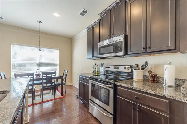 a kitchen with stainless steel appliances granite countertop a stove a sink and a microwave