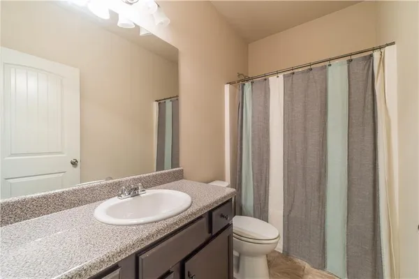 a bathroom with a granite countertop sink toilet and a mirror