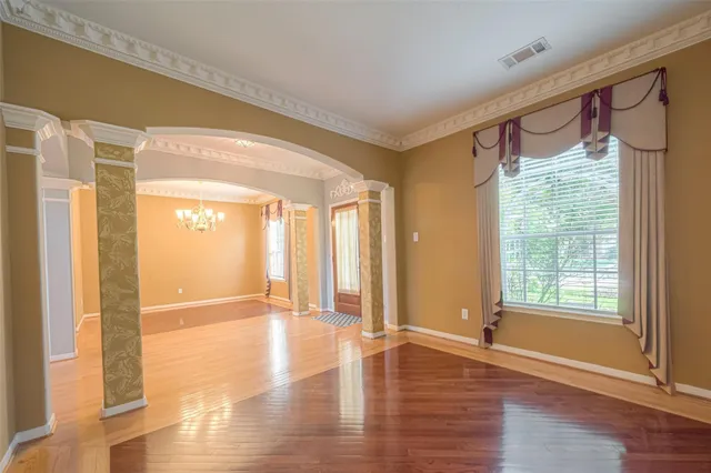 a view of an empty room with wooden floor and a window