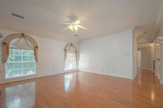 a view of empty room with wooden floor and fan
