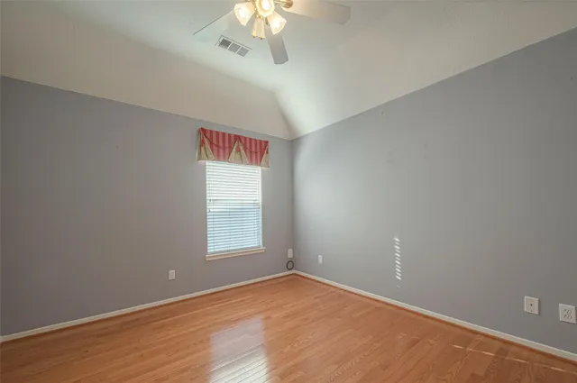 an empty room with a chandelier fan and windows