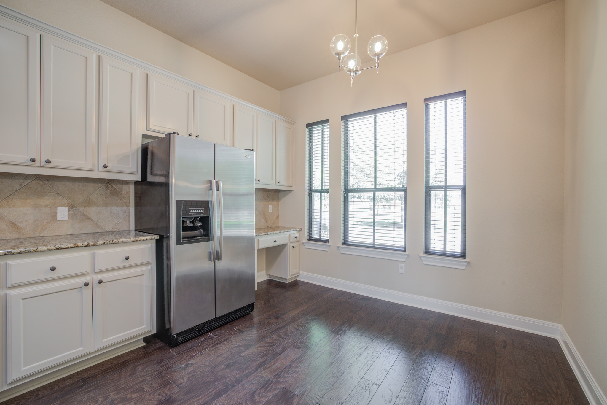 4524 Berkman Drive Austin, TX 78723 - Photo 10 of 38 Kitchen area featuring white cabinetry, a stainless steel refrigerator, stone countertops, and wood-finish flooring
