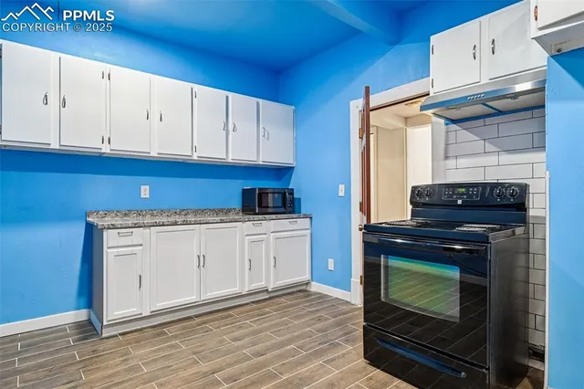 a kitchen with granite countertop white cabinets and appliances