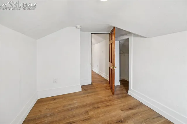 a view of an empty room with wooden floor and closet