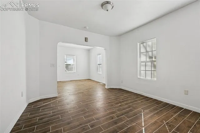 a view of an empty room with window and wooden floor