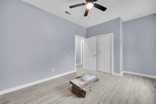 an empty room with wooden floor and ceiling fan