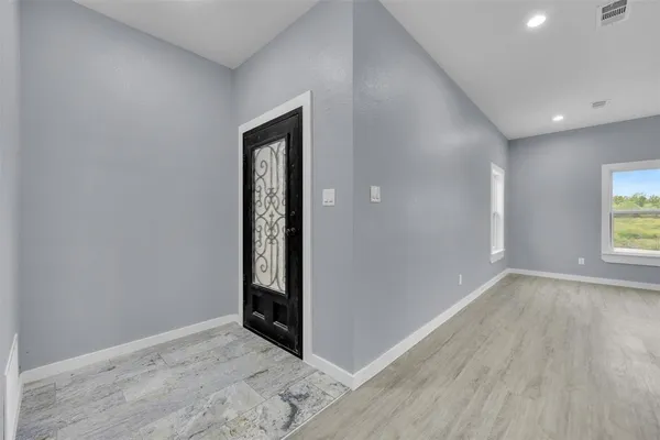 an empty room with wooden floor and windows