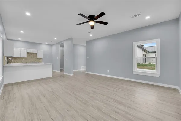 a view of an empty room with window and wooden floor