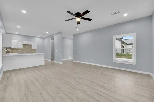 a view of an empty room with window and wooden floor